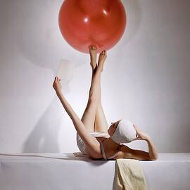 A Model Balancing A Red Ball On Her Feet by Horst P Horst